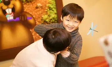 Young child hugging adult at Smile Lodge, warm indoor setting with decorative elements.