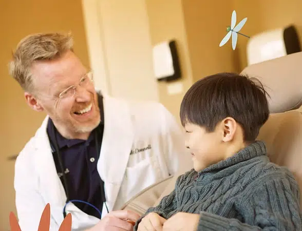 Doctor in white coat examining young patient in clinical setting at Smile Lodge.