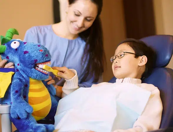 Woman and child interact with blue puppet during therapy session at The Smile Lodge.