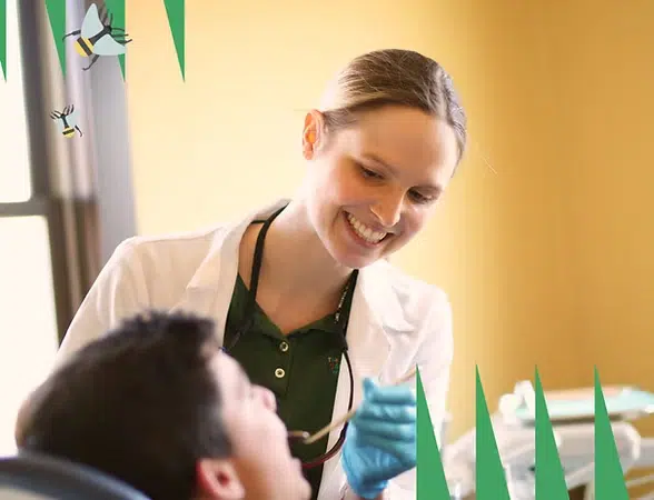 Healthcare provider smiling while interacting with young patient in bright, cheerful medical clinic room.
