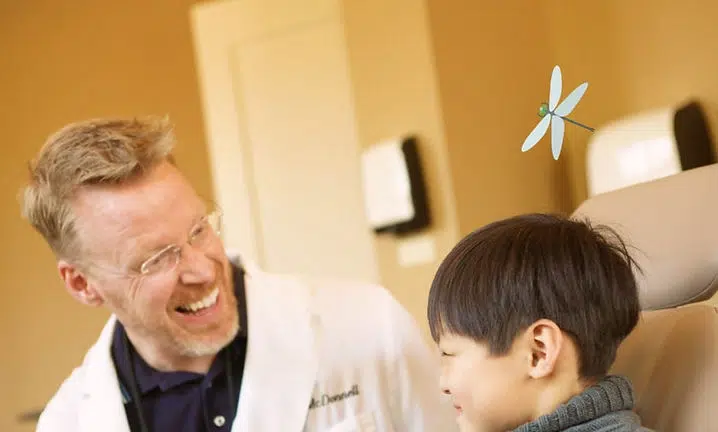 Doctor in white coat smiling while examining young boy in clinical setting at Smile Lodge.