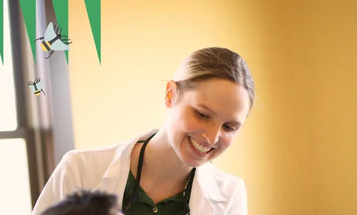 Smiling woman in apron and white coat at The Smile Lodge dental practice