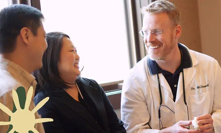 Three people engaged in conversation at Smile Lodge, professional dental setting with warm lighting.