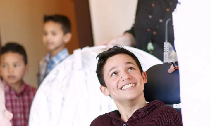 Children and adults indoors looking upward with smiles in a casual home setting.