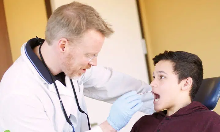 Healthcare provider examines young patient's mouth during dental checkup at clinic.