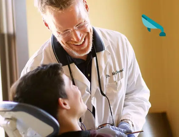 Dentist examines young patient in clinical setting at The Smile Lodge dental office.