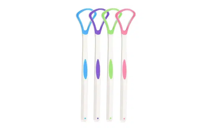 Four colorful tongue scrapers with loop handles arranged in a row on white background.