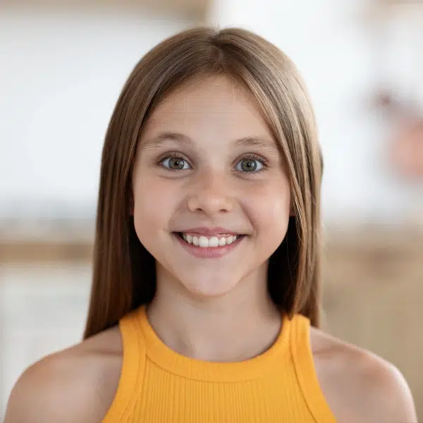 Smiling young girl in yellow tank top, indoor portrait with blurred background