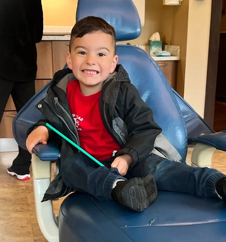 Young child sitting in dental chair, smiling at Smile Lodge office.